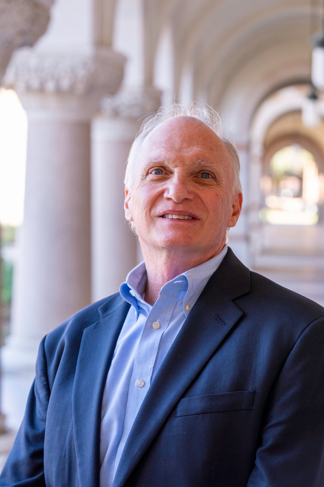 Portrait of Skip York in a navy blazer beneath a stone arcade