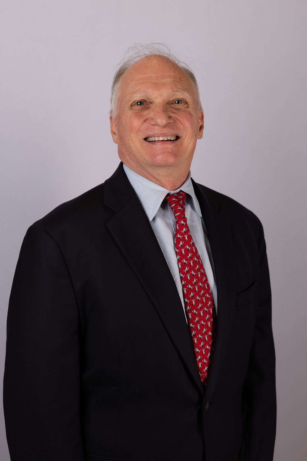 Skip York, author of Mind the Gap, in a navy suit and red tie
